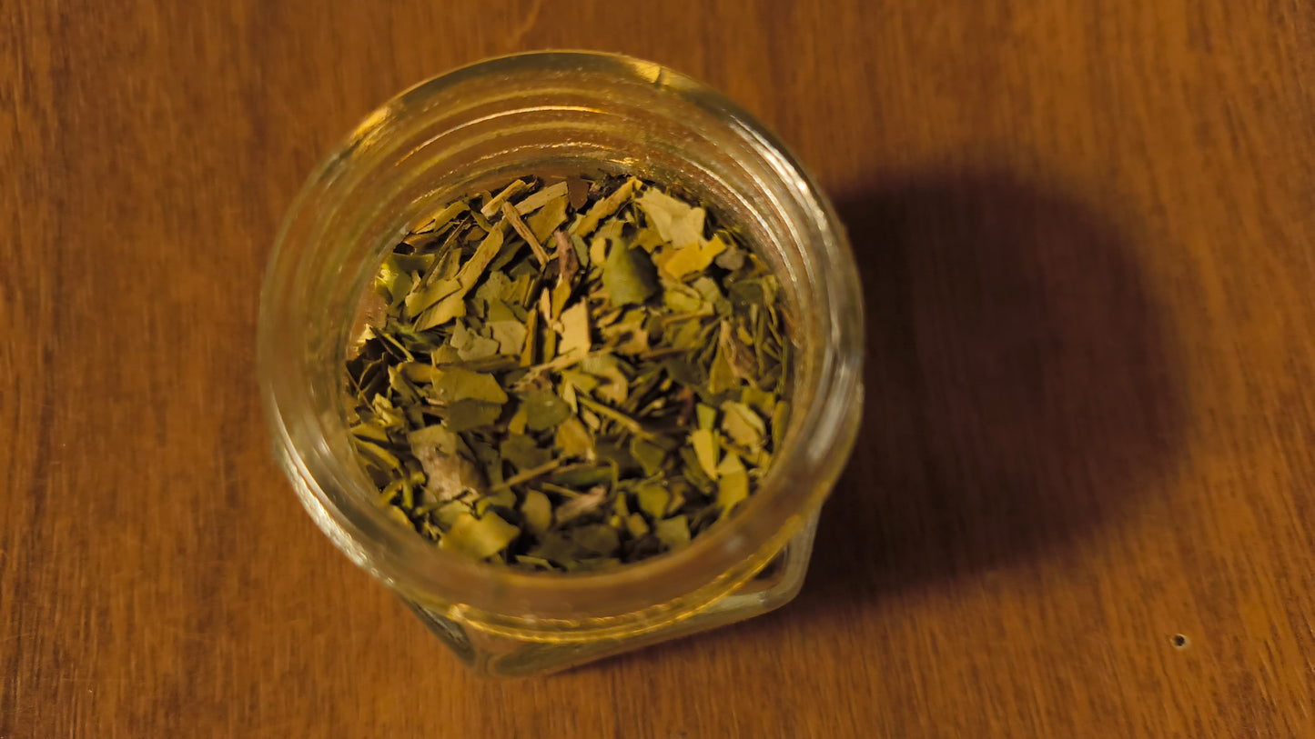 Glass jar filled with dried herbs on a wooden surface