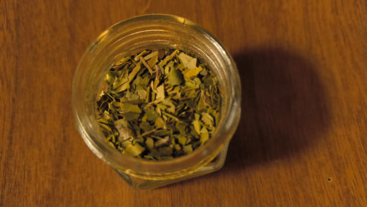 Glass jar filled with dried herbs on a wooden surface